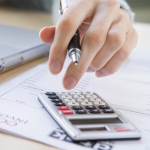 hand holding a pen over a calculator